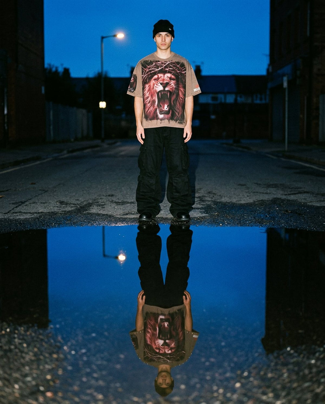 Man in a Stray lion graphic tee reflected in a puddle at dusk